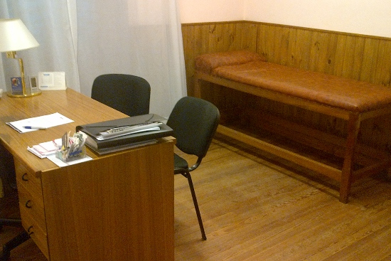 Consultorio con escritorio y camilla de examen de madera