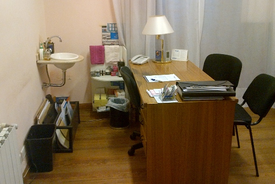 Consultorio con escritorio, sillas y lavabo